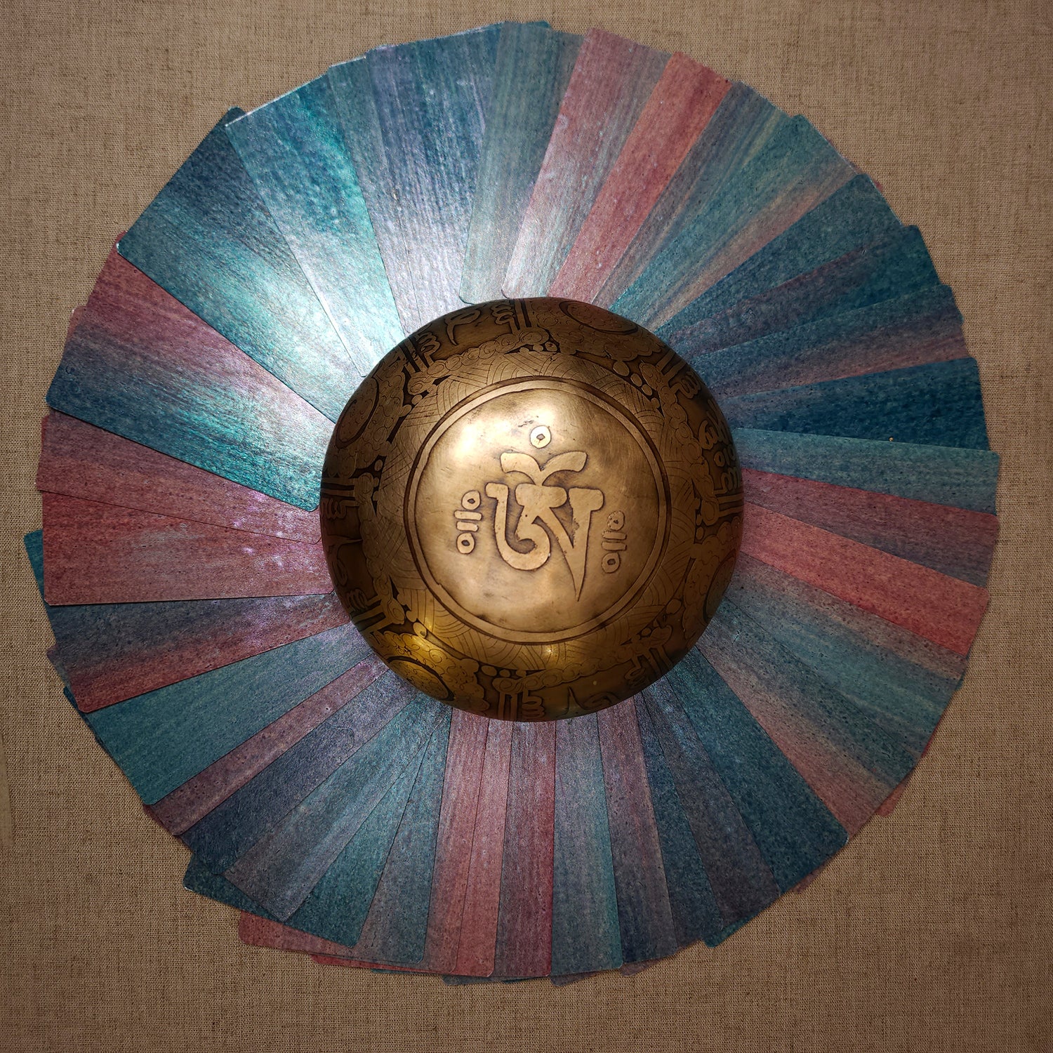 une couronne de cartes au couleurs irisée et nacrées entouran un bol tibétain portant le signe OM 